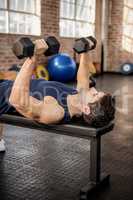 Man lifting dumbbells lying on exercise bench