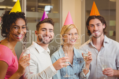 Smiling colleagues holding champagne flute in birthday party