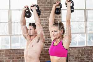 muscular serious couple with kettlebells