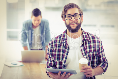 Portrait of smiling businessman holding coffee cup and digital t