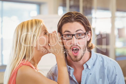 Businessman listening to rumor which female colleague is whisper