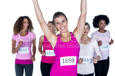 Portrait of smiling winner athlete with arms raised and others r