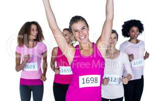 Portrait of smiling winner athlete with arms raised and others r