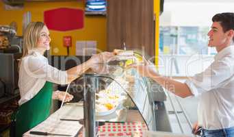 Female shop owner serving sandwich to male customer