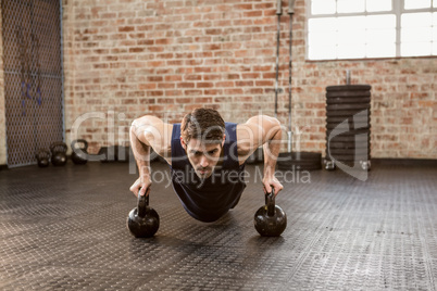 Man doing push ups holding kettlebell