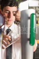 Close-up of bartender holding glass at beer dispenser