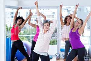 Group of cheerful women exercising with arms raised