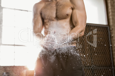 Midsection of a muscular man applying chalk powder