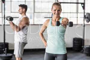 couple exercising with dumbbells in gym