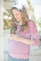 Happy woman text messaging by window
