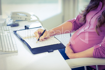 Midsection of businesswoman writing in diary