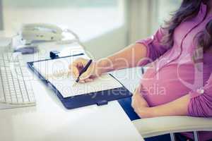 Midsection of businesswoman writing in diary