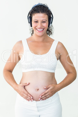 Pregnant woman listening to music while touching her belly