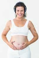 Pregnant woman listening to music while touching her belly