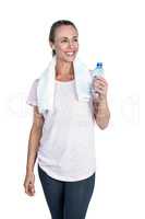 Happy sporty woman holding bottle while listening music