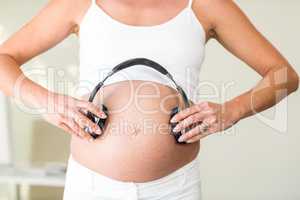 Midsection of woman with headphones on belly
