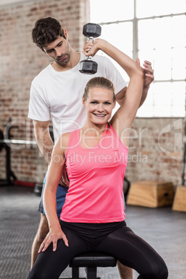 Fit woman lifting dumbbells with trainer