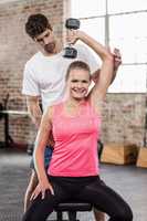 Fit woman lifting dumbbells with trainer