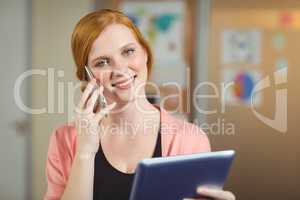Happy businesswoman looking at digital tablet while talking on p