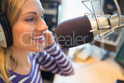 Happy young female radio host broadcasting in studio