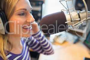 Happy young female radio host broadcasting in studio