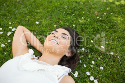 Happy woman relaxing with hand behind head on grassland