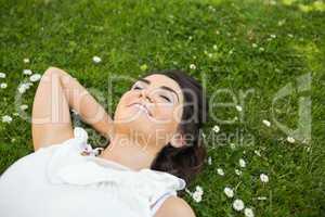 Happy woman relaxing with hand behind head on grassland