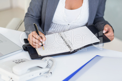 Businesswoman writing on book