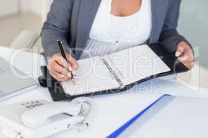 Businesswoman writing on book