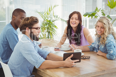 Man showing digital tablet to coworkers at desk