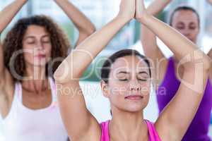 Women meditating with joined hands and arms raised