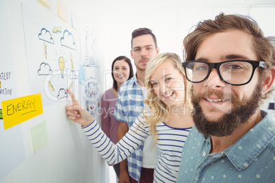 Portrait of smiling business team while standing by wall with st