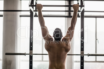 Muscular man lifting himself up and down