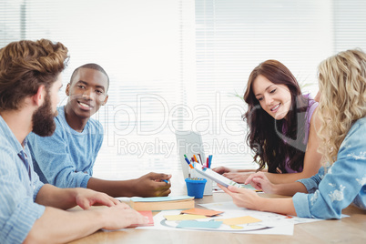 Smiling business people discussing while working at desk