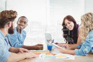 Smiling business people discussing while working at desk