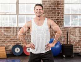 Smiling muscular man with hands on hips