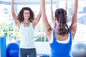 Cropped image of women with arms raised in fitness studio