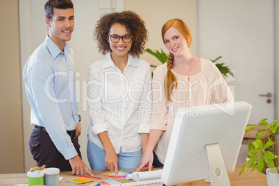 Smiling business people standing by desk