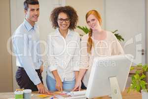 Smiling business people standing by desk