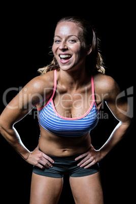 Portrait of cheerful female athlete with hand on hip