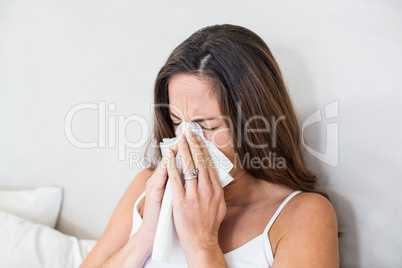 Woman sneezing with tissue on mouth