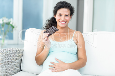 Portrait of woman with chocolate bar on sofa
