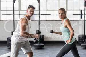 Couple exercising with dumbbells in gym