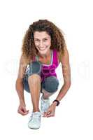 Portrait of happy young woman tying shoelace