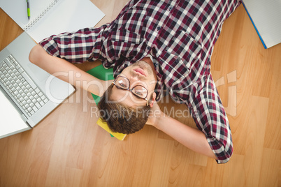 Hipster wearing eye glasses lying on hardwood floor
