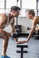couple exercising with dumbbells in crossfit gym
