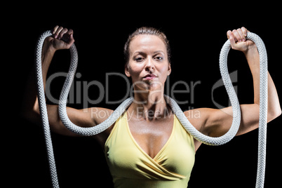 Healthy woman holding rope around neck with arms raised