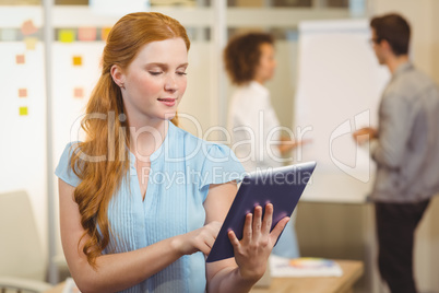 Confident businesswoman using digital tablet with colleagues