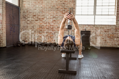 Man lifting dumbbell lying on bench