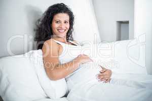 Happy pregnant woman resting in bed